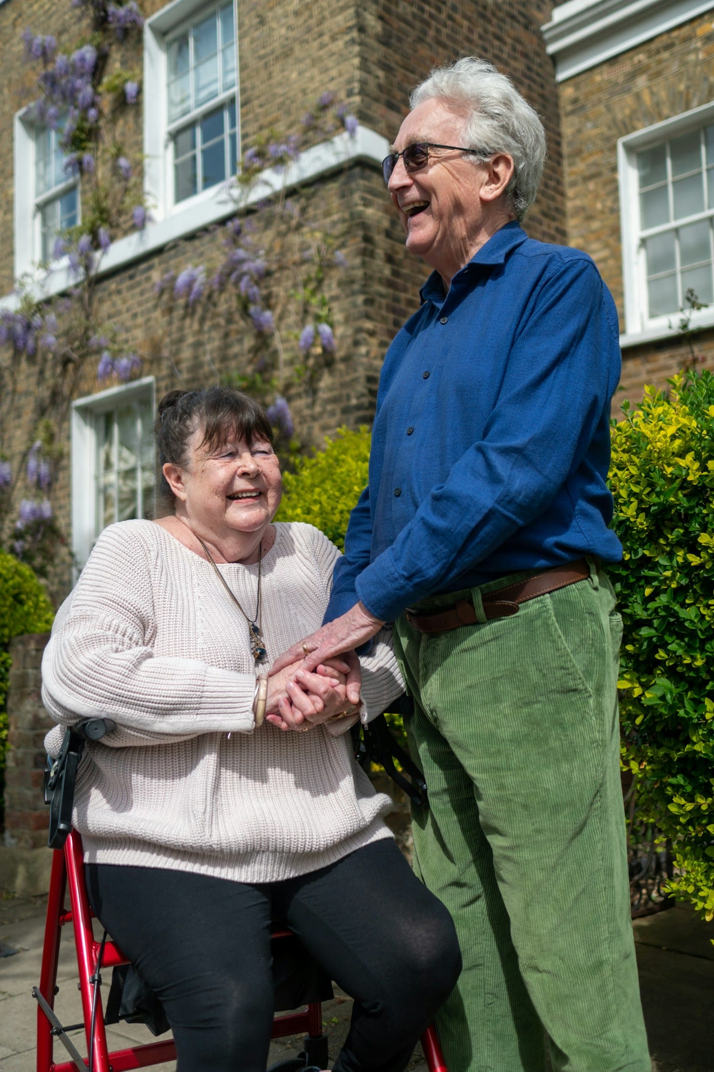 An older couple laughing together outside their house